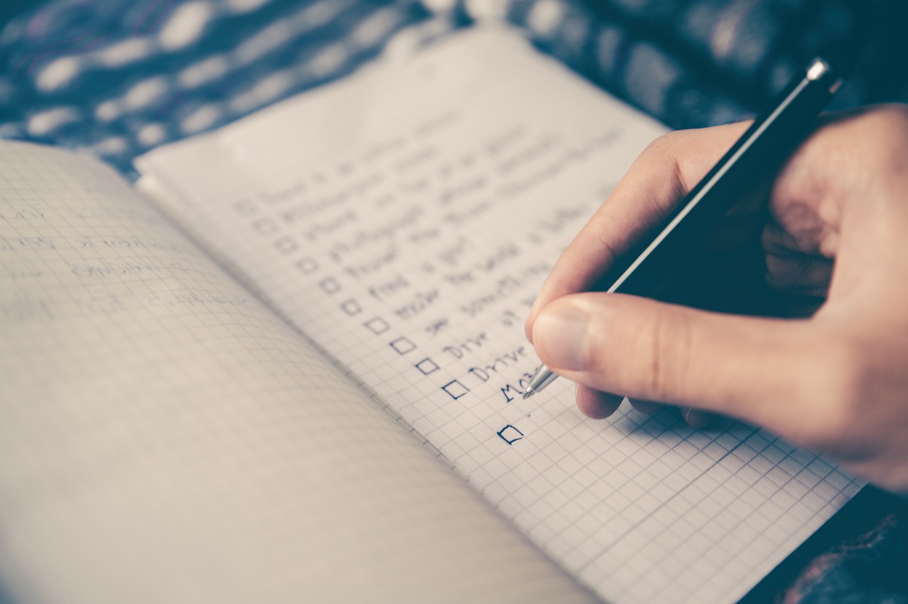 hand with pen writing task list in notebook.
